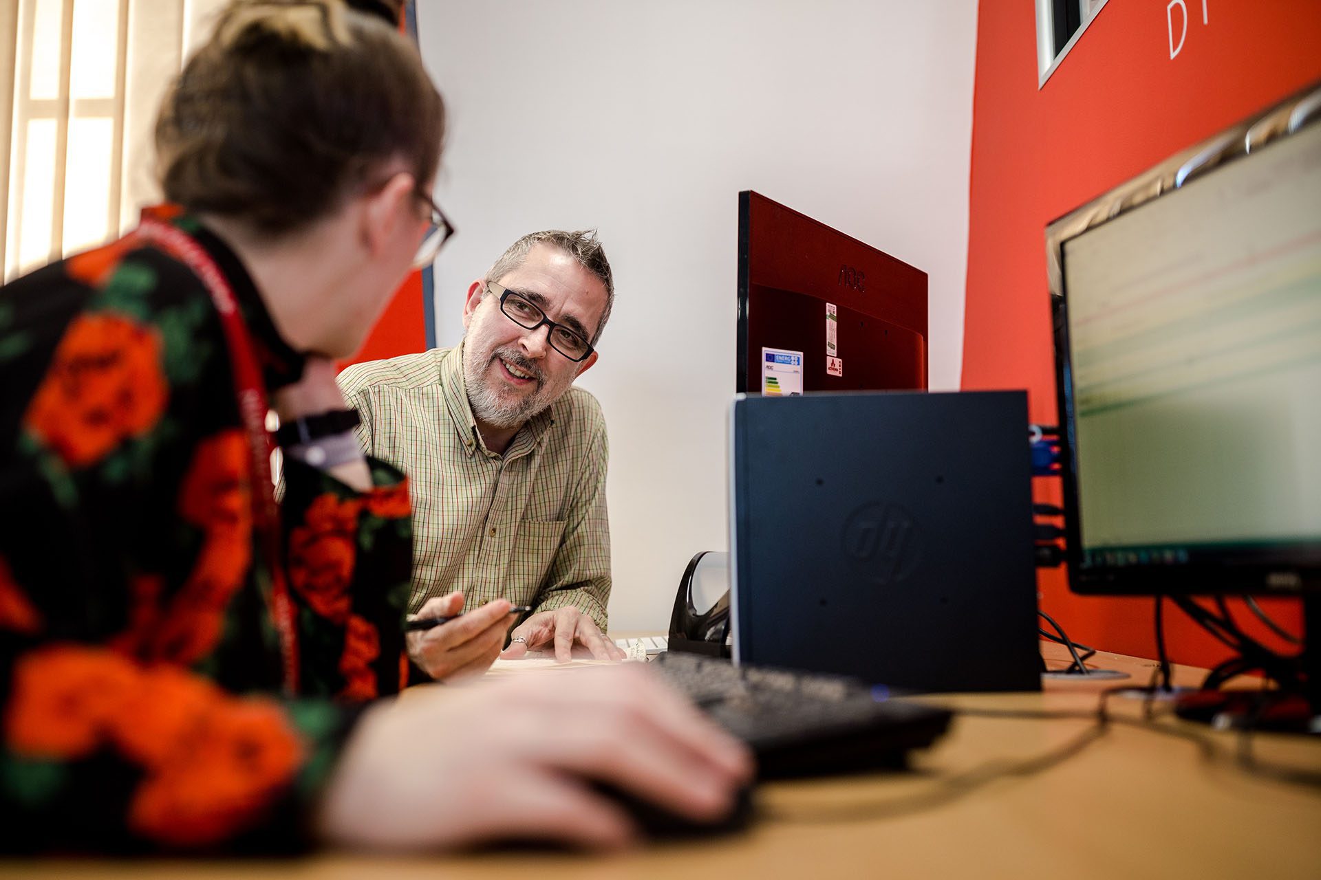 an image of two employees at a desk having a conversation